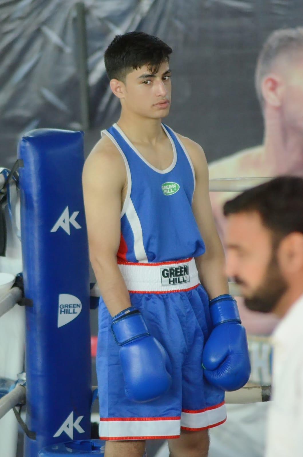 Boxer in blue kit waiting ringside before his bout