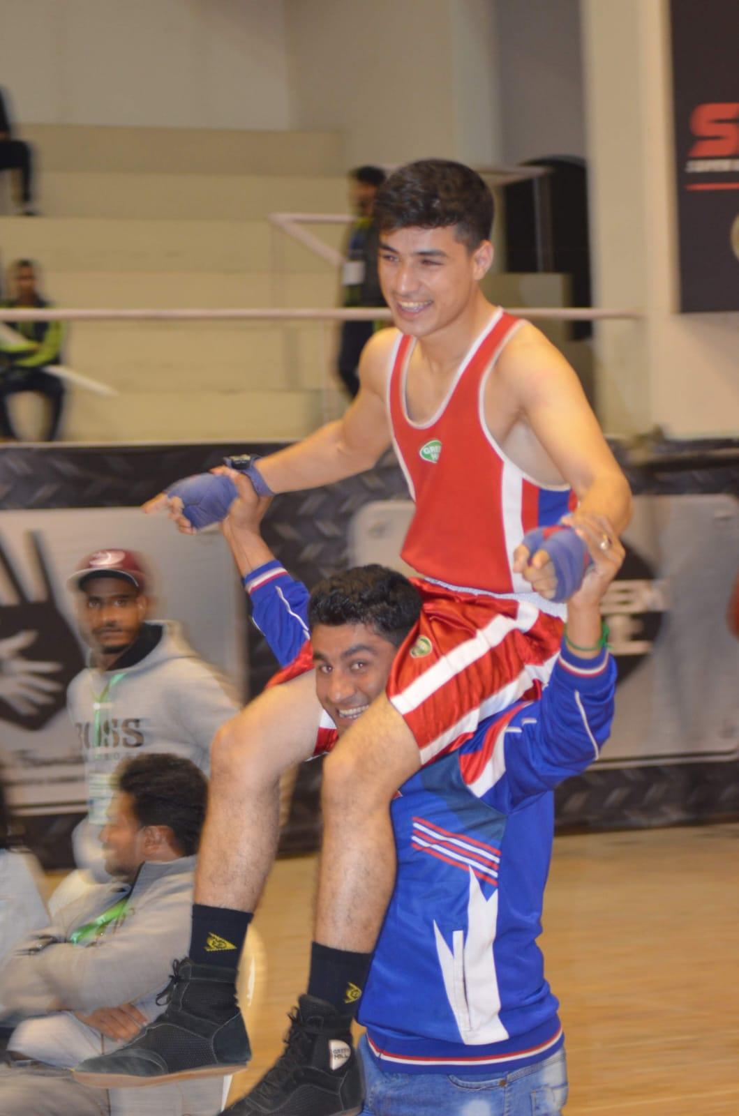 A coach carrying a winning boxer on his shoulders after the decision